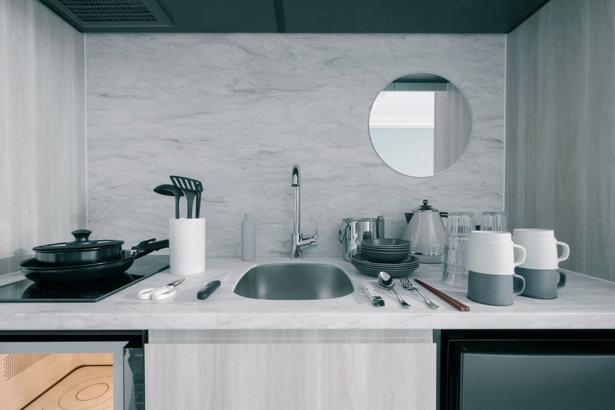 A modern kitchen with a sink, stove, and various utensils.