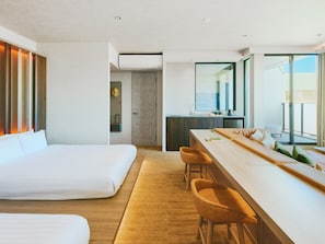 A modern hotel room with a large bed, a dining area with bar stools, a kitchenette, and a view of the outdoors. - FAV LUX NAGASAKI (Nagasaki)