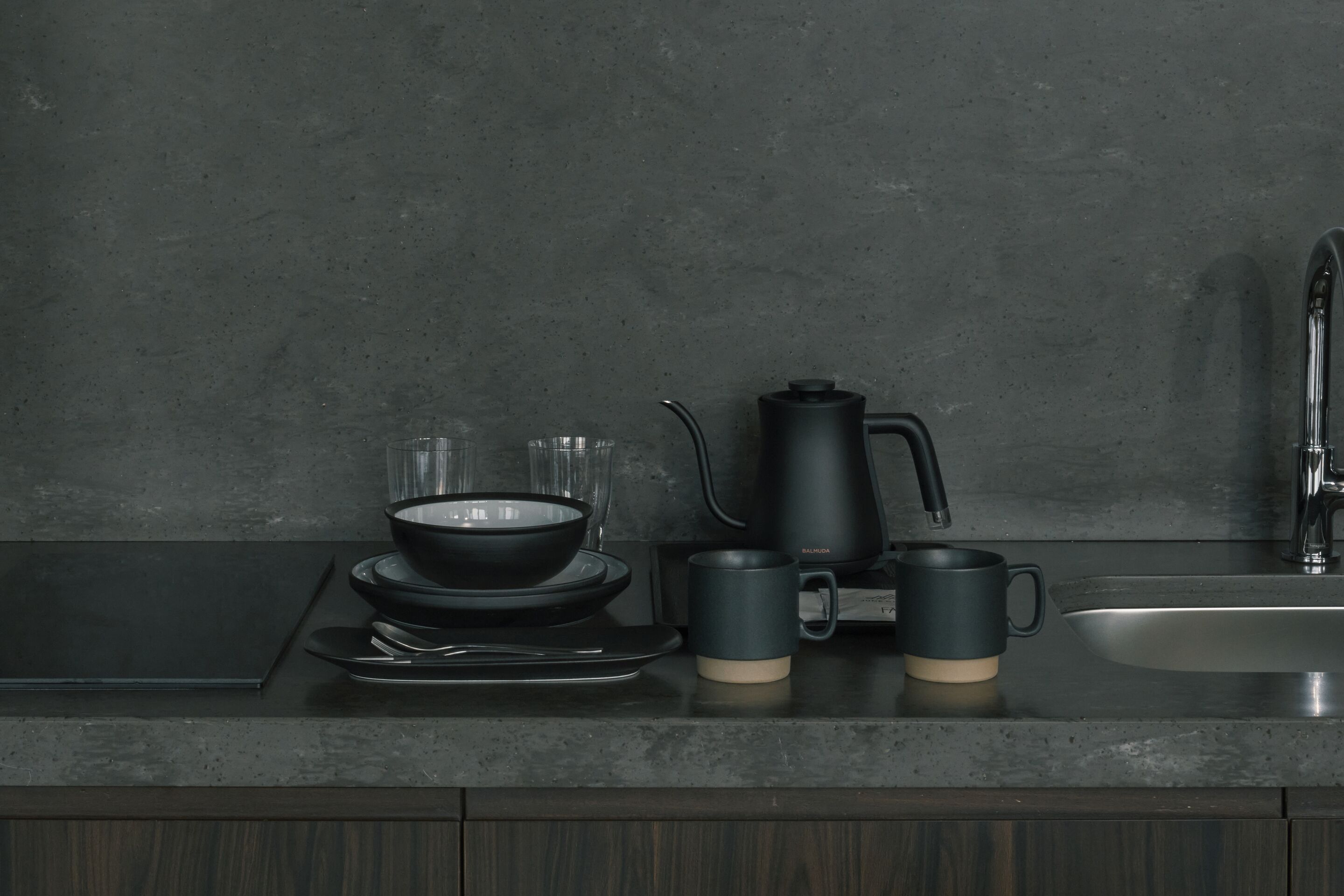 A kitchen counter with a coffee maker, a bowl, and two cups.