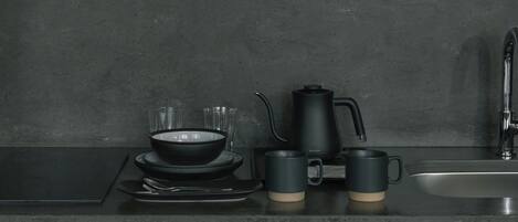 Una encimera de cocina con una cafetera, un cuenco y dos tazas.