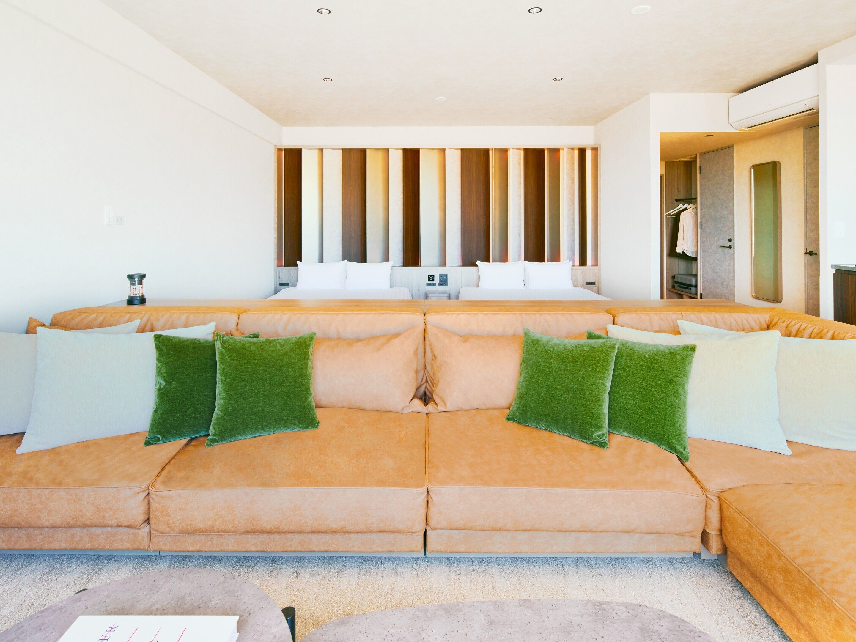 Habitación de hotel moderna con un amplio sofá modular, un revestimiento de listones de madera y un vestidor.