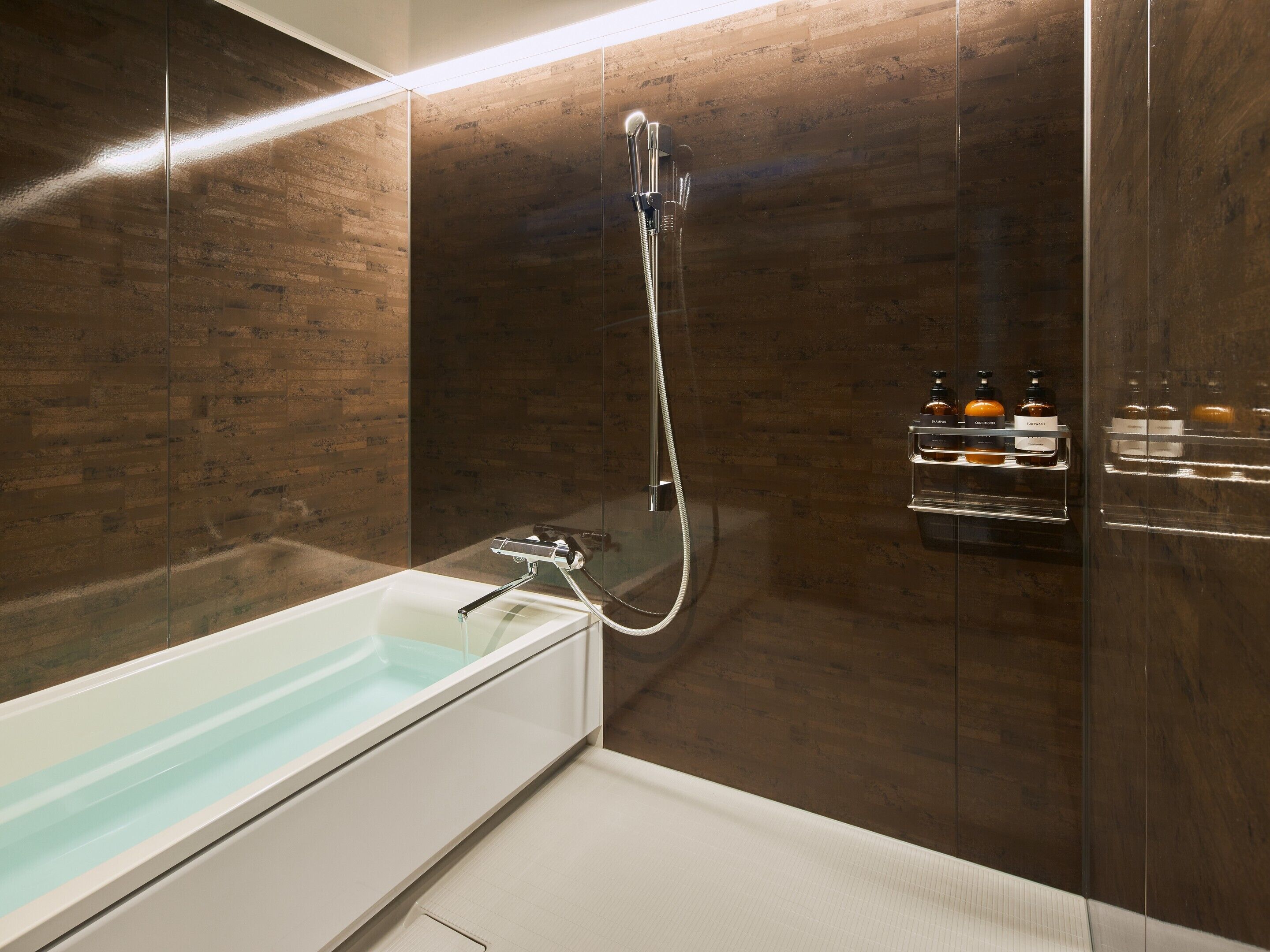 Een moderne badkamer met een douchecabine van glas, een witte badkuip en een plank met toiletartikelen.