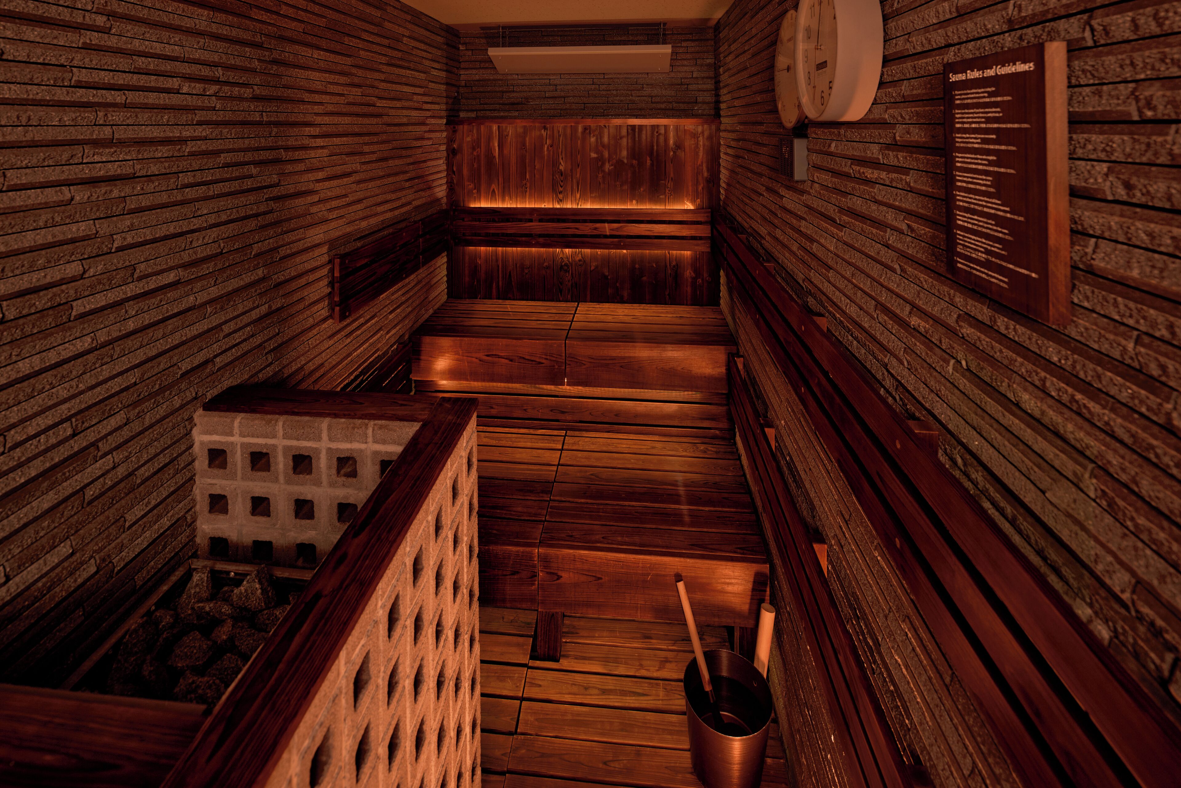 Una sauna con bancos de madera y una pared de ladrillo.