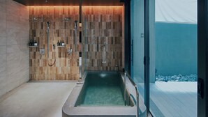 A modern bathroom with a freestanding bathtub, a shower area, and a glass door leading to an outdoor area. - FAV LUX NAGASAKI (Nagasaki)