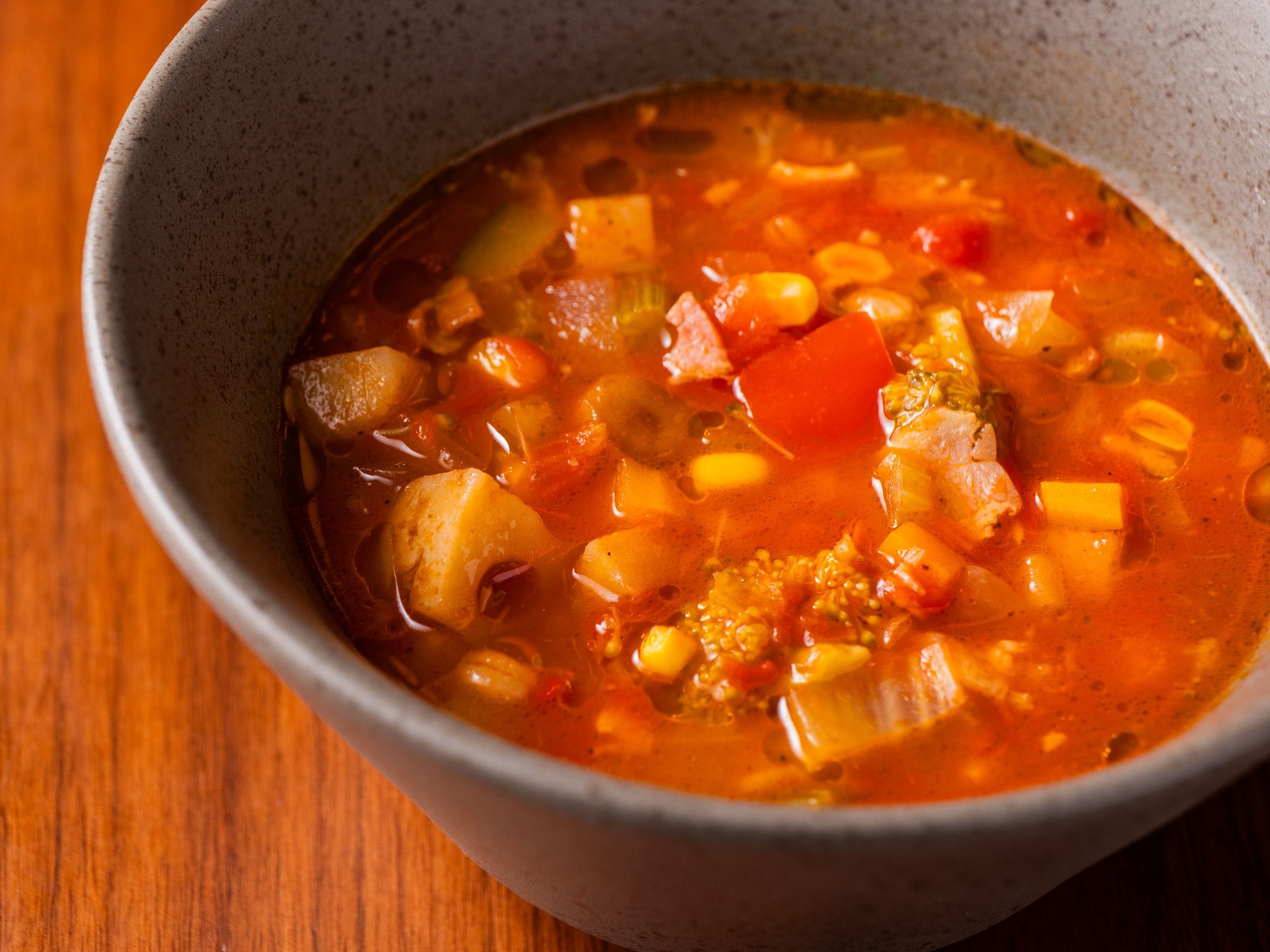 Un tazón de sopa con diversos vegetales y un caldo transparente.
