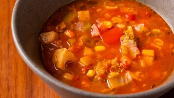 A bowl of soup with various vegetables and a clear broth.