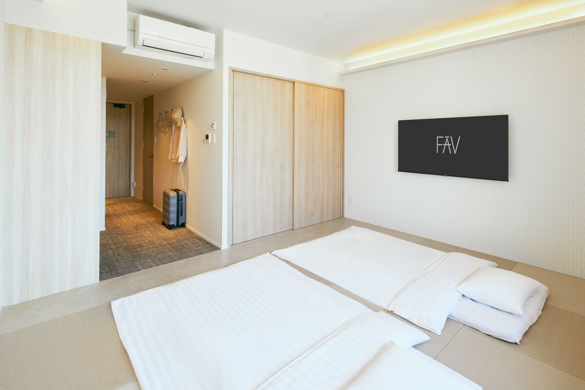 A hotel room with two beds, a wardrobe, a coat rack, and a flat-screen TV.