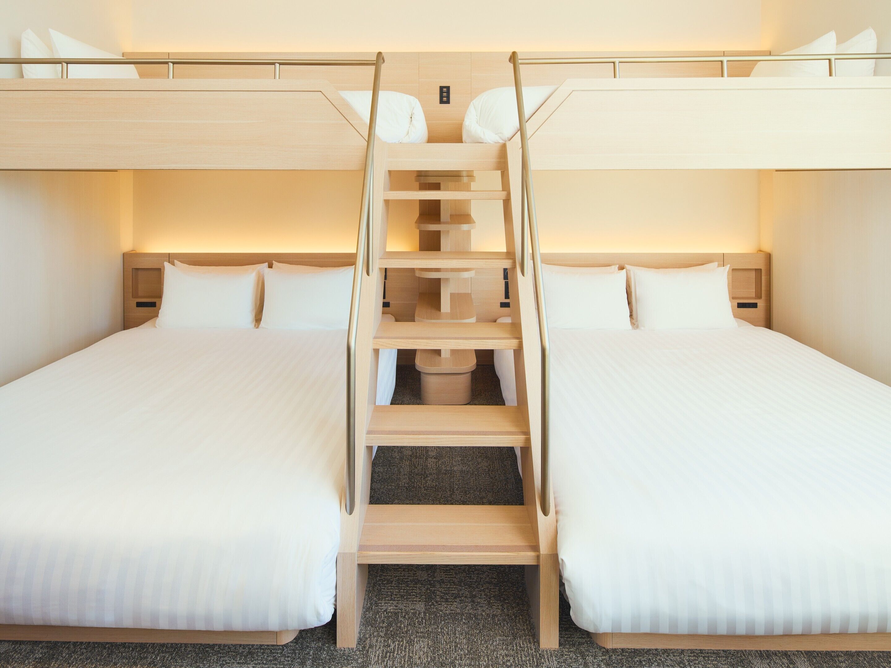 A hotel room with two beds, a central staircase, and a wooden headboard.