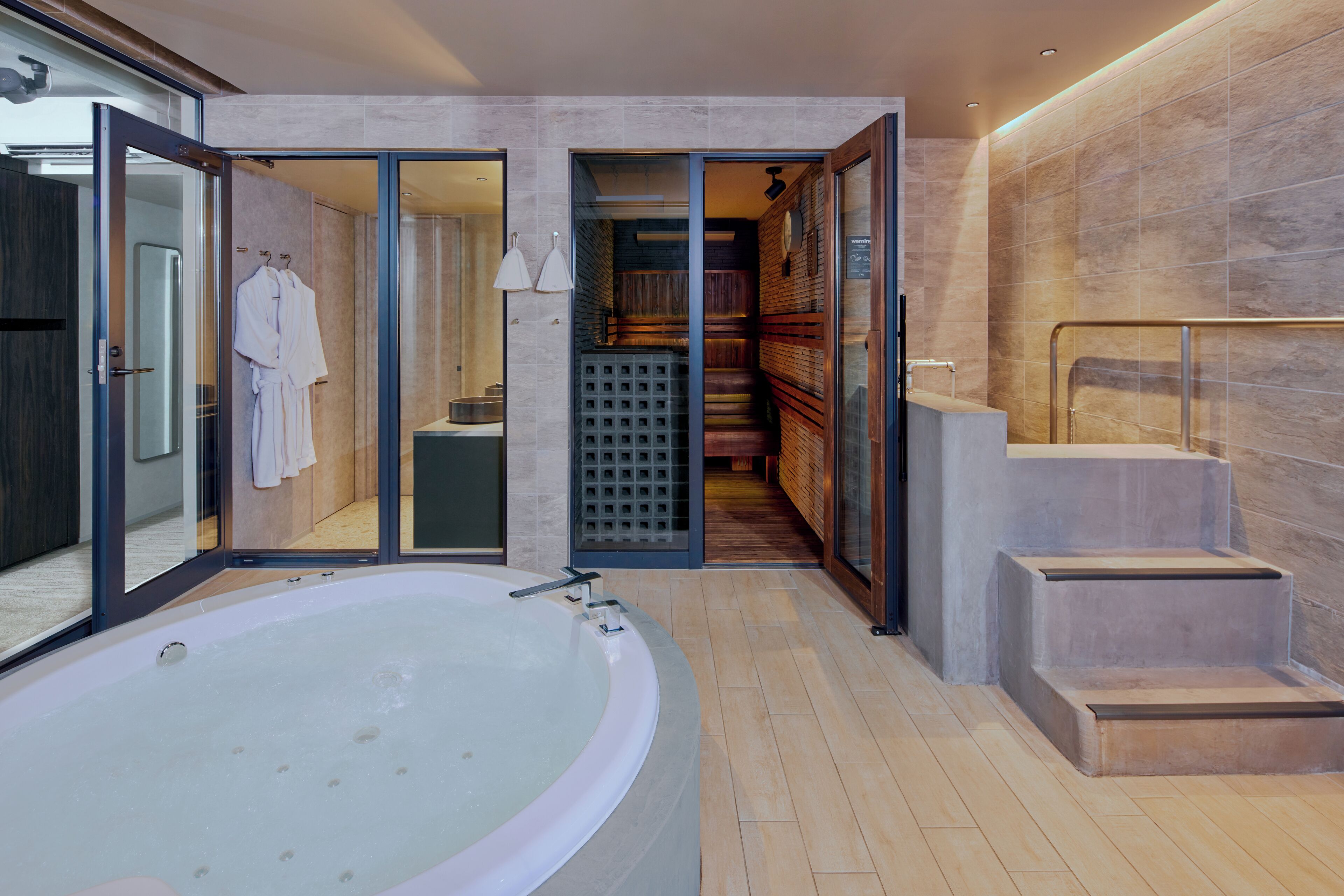 A modern bathroom with a large bathtub, a shower area, and a visible staircase leading to another level.
