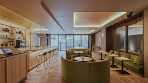 A modern interior with a bar area, seating with round tables, and a view through large windows. - FAV LUX NAGASAKI (Nagasaki)