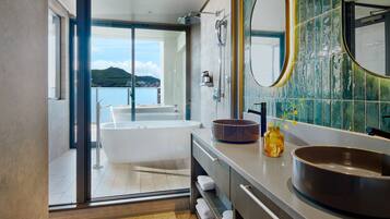 A modern bathroom with a bathtub, a large mirror, and a view of a body of water.