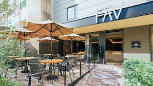 An outdoor seating area with tables and chairs, umbrellas, and a brick floor. - FAV LUX NAGASAKI (Nagasaki)