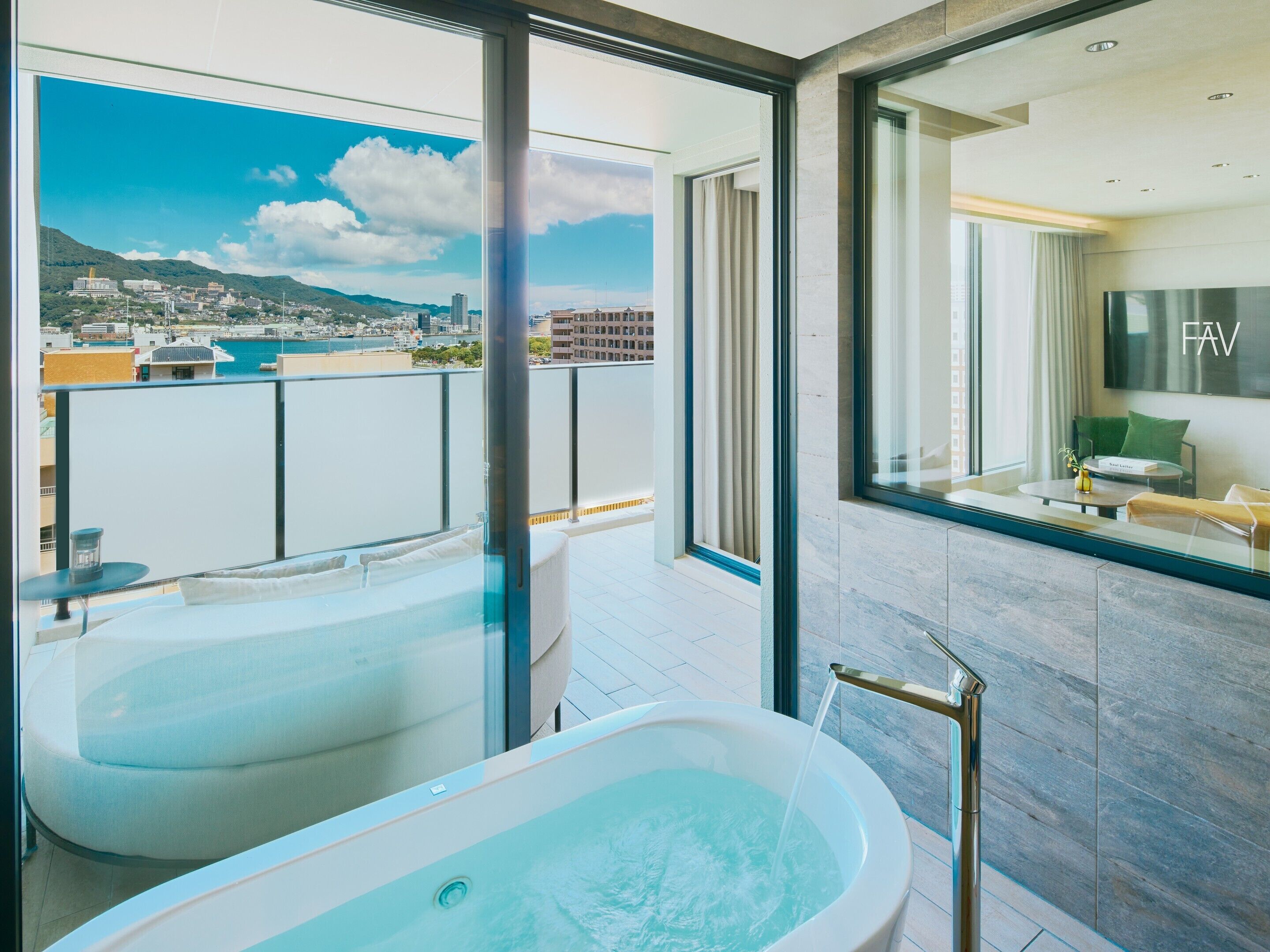 A modern bathroom with a bathtub, a shower, and a large window offering a city view.