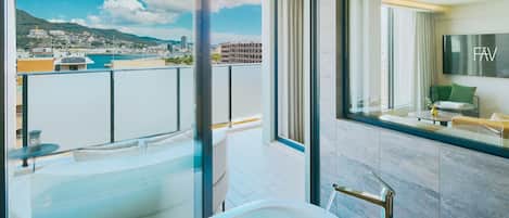 Un baño moderno con bañera, ducha y un amplio ventanal con vistas a la ciudad.
