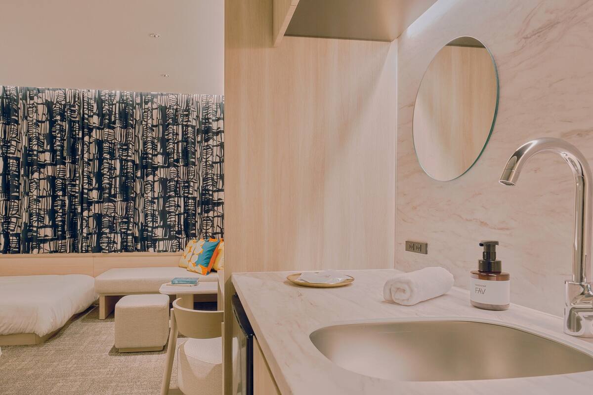 A modern bathroom with a large sink, a mirror, and a towel on the counter.