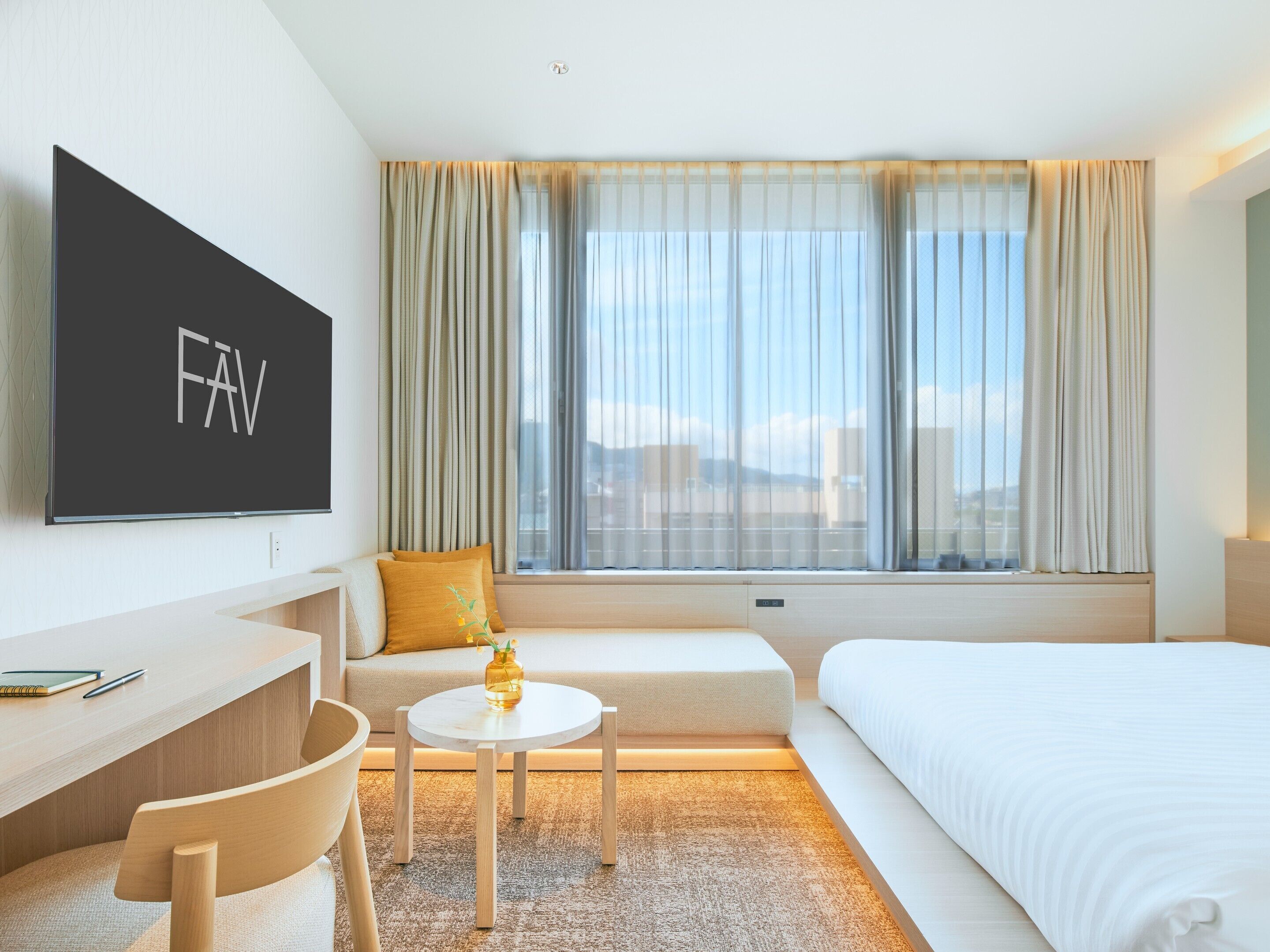Habitación de hotel con cama, escritorio, silla, televisor y ventana con cortinas.