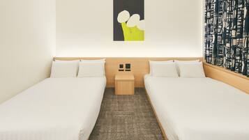 A hotel room with two single beds, a small bedside table, a wall-mounted light, and a patterned curtain.