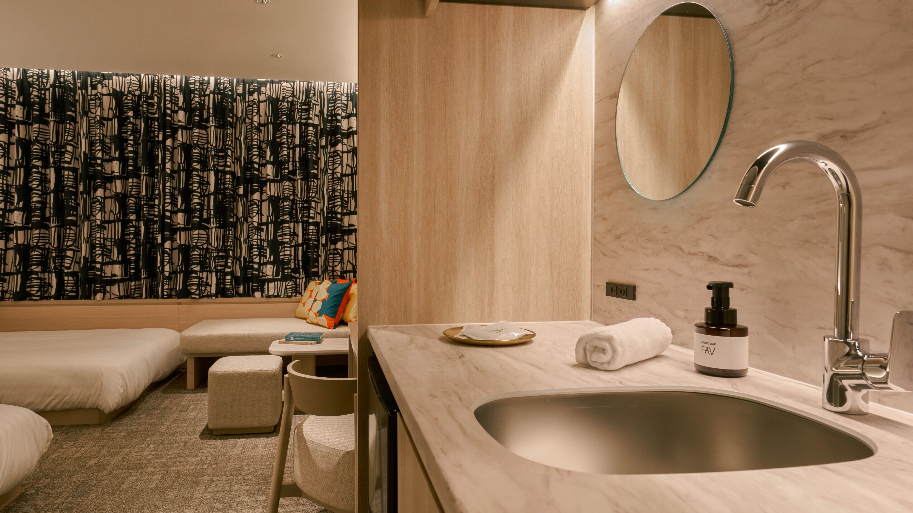 A modern bathroom with a marble sink, a handheld showerhead, and a towel on the counter.