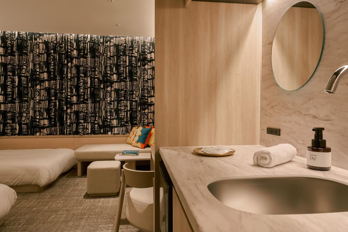 A modern bathroom with a marble sink, a handheld showerhead, and a towel on the counter.