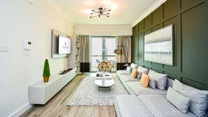 A modern living room with a sofa, coffee table, and a TV on the wall. - New 1BR Apartment - 8 Blvd Walk -  WLK (Dubai)