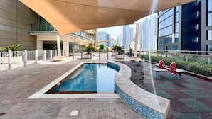 A rooftop pool area with a swimming pool, exercise equipment, and a view of the city skyline. - New 1BR Apartment - 8 Blvd Walk -  WLK (Dubai)