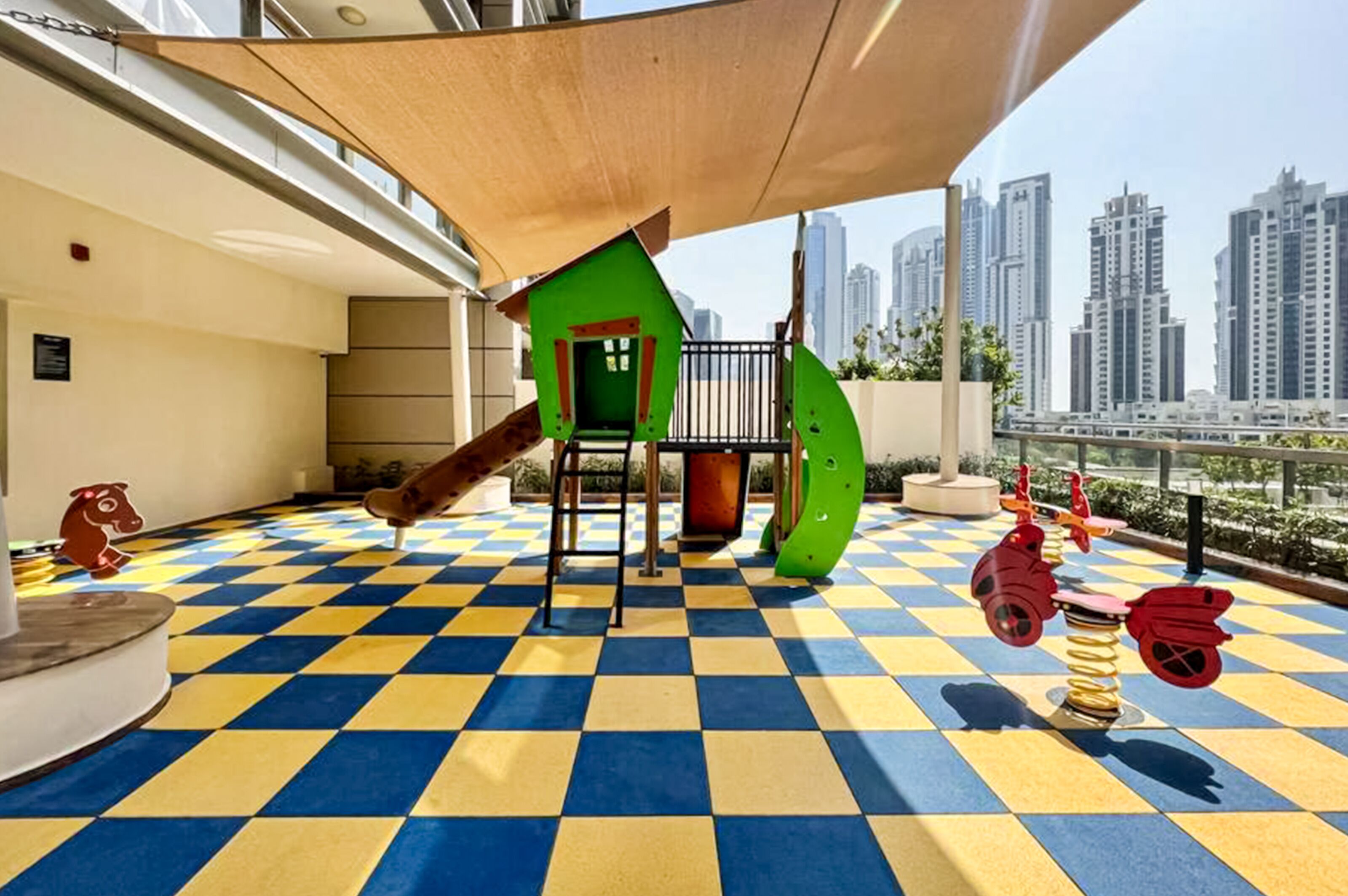 A rooftop playground with a checkered floor, a slide, and colorful play equipment.