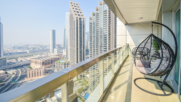 A balcony with a hanging chair, a city view, and high-rise buildings. - New 1BR Apartment - 8 Blvd Walk -  WLK (Dubai)