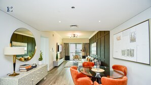 A modern living room with a dining area, featuring a sofa, chairs, a coffee table, and a large mirror. - New 1BR Apartment - 8 Blvd Walk -  WLK (Dubai)