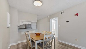 Un coin repas avec une table et des chaises en bois, une cuisine avec des meubles blancs et un plancher de couleur claire.