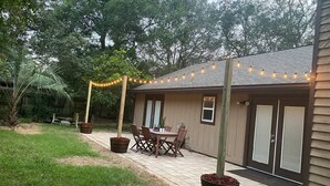 Un bâtiment en bois doté d’un patio, de sièges en plein air et de guirlandes lumineuses.