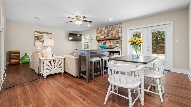 Une cuisine spacieuse avec un coin repas, un plancher en bois et un mur d’accent en pierre.