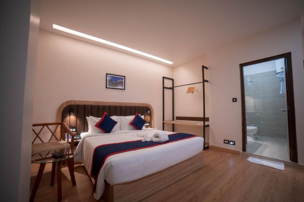 Une chambre d’hôtel moderne dotée d’un grand lit, d’un bureau, d’une chaise et d’une douche à parois de verre.