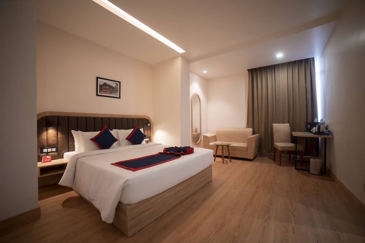 A modern hotel room with a large bed, a desk, a chair, and a small table.