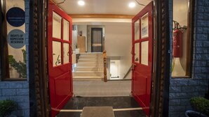 A hotel entrance with a red door, a staircase, and a fire extinguisher on the wall. - Zip By Spree Hotels Gangtok (Gangtok)