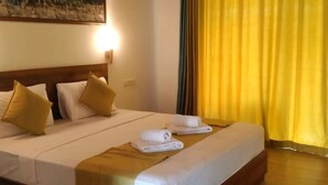 A neatly made bed with white linens and two gold pillows, a folded towel, and a wooden headboard. - Sigiriya Retreats (Sigiriya)