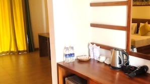 A hotel room with a wooden desk, a kettle, a phone, and a mirror reflecting a bed with yellow pillows. - Sigiriya Retreats (Sigiriya)