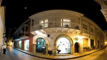 Um edifício histórico com fachada curva, janelas em arco e uma varanda com grades.