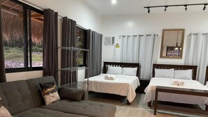 A hotel room with a sofa, two beds, a metal shelf, and a view of the outdoors. - Crystal Cove (Sipalay)