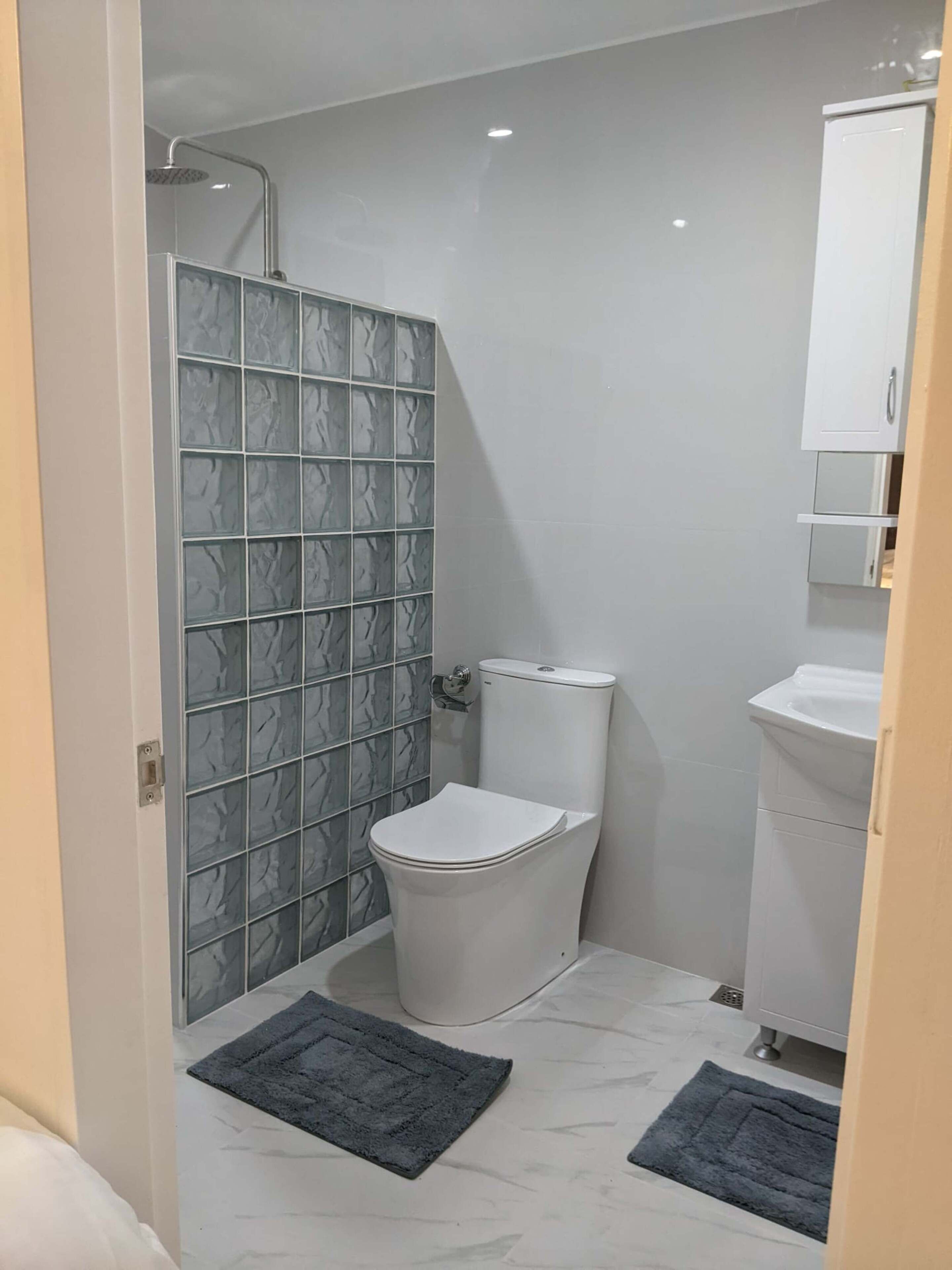 A small bathroom with a toilet, a sink, and a shower.