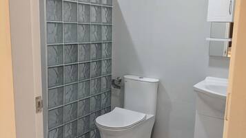 A small bathroom with a toilet, a sink, and a shower.
