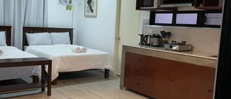 Une chambre d’hôtel moderne avec deux lits, une kitchenette et des luminaires suspendus.