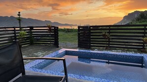 A pool area with a view of mountains and a sunset. - Crystal Cove (Sipalay)