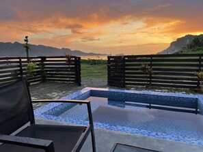 A pool area with a view of mountains and a sunset. - Crystal Cove (Sipalay)