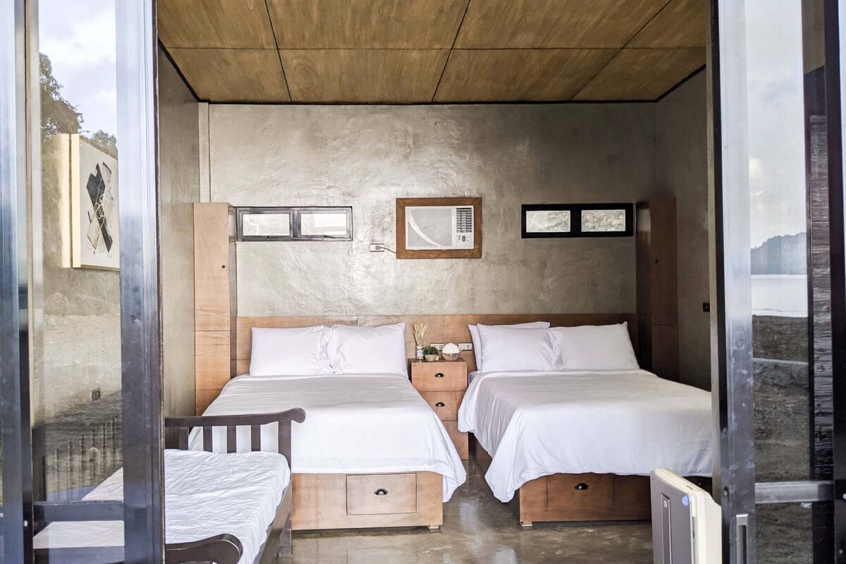 Una habitación con dos camas, cabeceros de madera y suelo de hormigón.