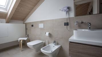 Een moderne badkamer met een bidet, toilet, wastafel en een aan de muur bevestigde haardroger.