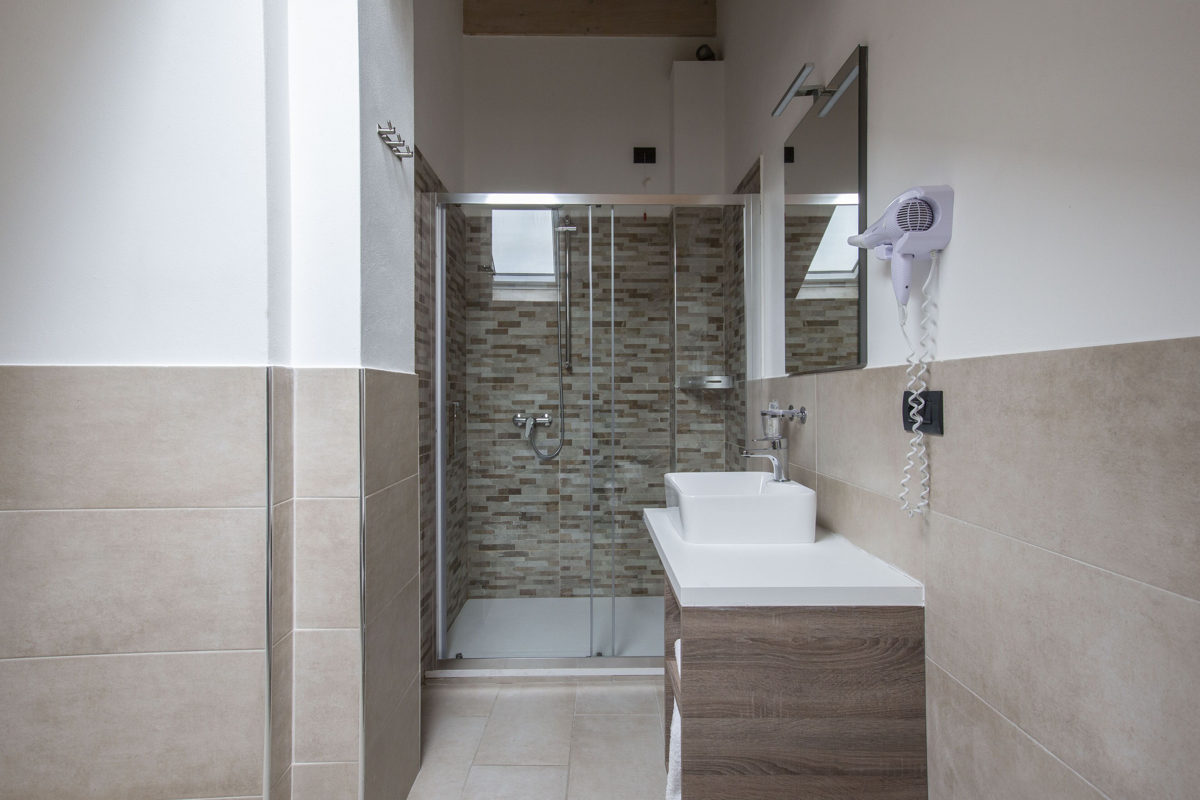 Une salle de bain moderne avec une douche en verre, un lavabo blanc et un miroir au-dessus du lavabo.