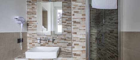 A modern bathroom with a rectangular sink, a mirror, a hairdryer, and a shower with a glass door.