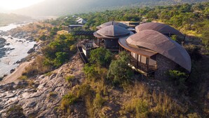 Un complejo turístico con varias construcciones en forma de cúpula, una costa rocosa y montañas al fondo.