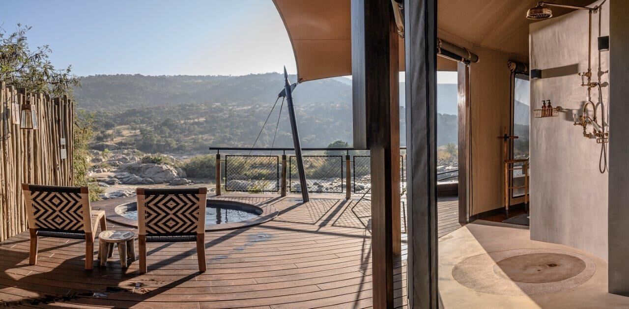 Une terrasse en bois avec un jacuzzi, des sièges d’extérieur et une vue sur les montagnes.