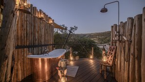 Una terraza de madera con una bañera, una ducha y faroles.